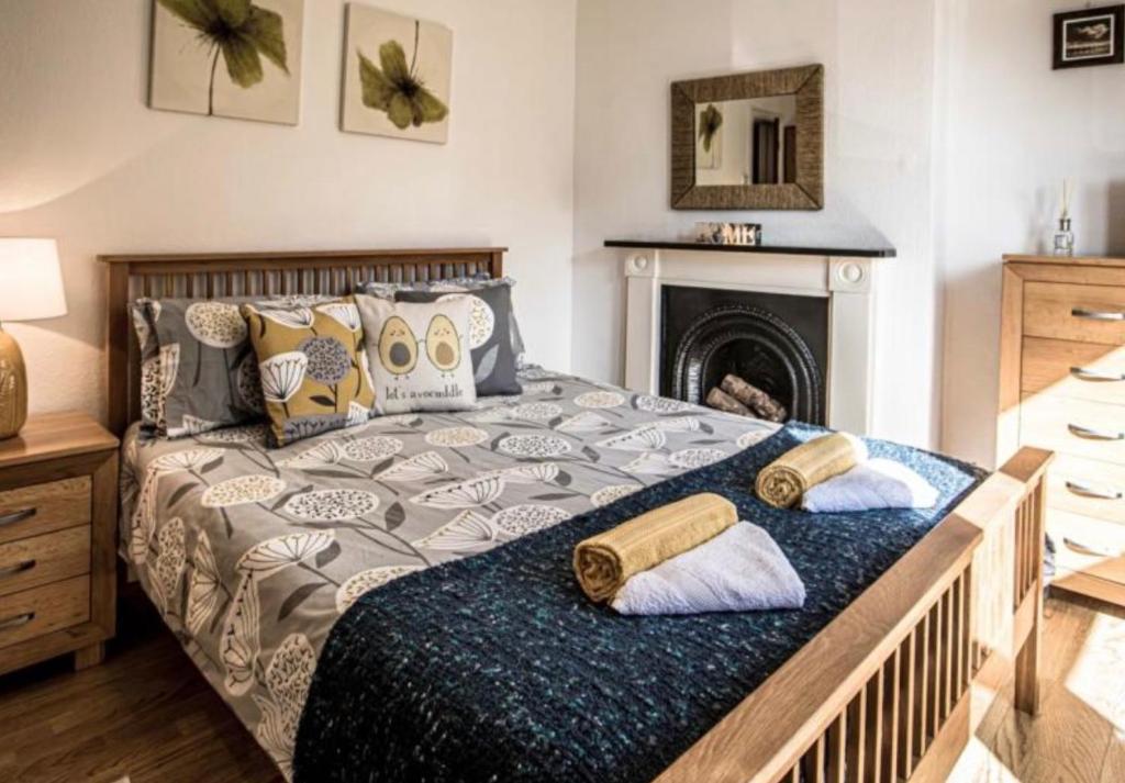 um quarto com uma cama com almofadas e uma lareira em Johaan em Caernarfon