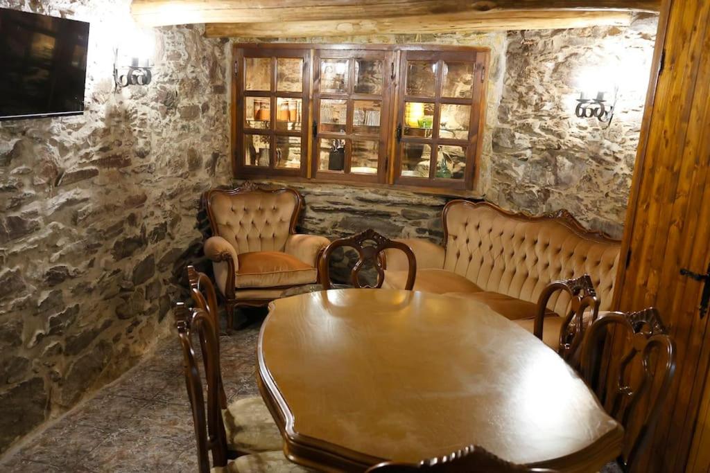 uma sala de jantar com uma mesa de madeira e cadeiras em A casa dos carros em Folgoso