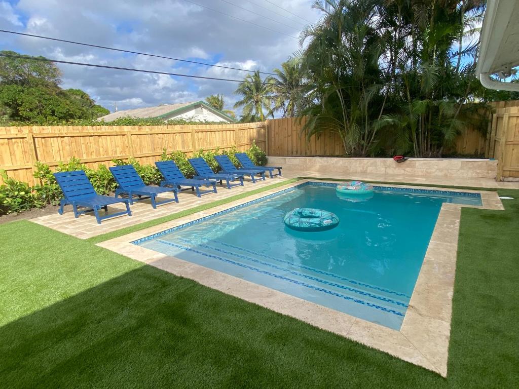 a swimming pool in a yard with blue chairs at Whitecaps Beach house in Delray Beach