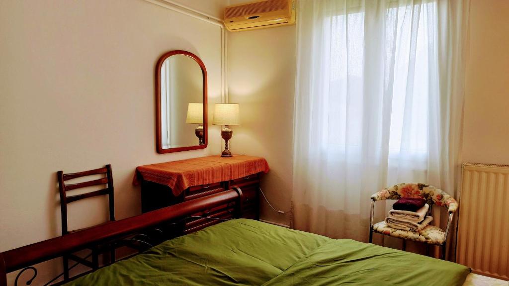 1 dormitorio con cama, espejo y silla en Nafpaktos The country home, en Kolovaíika