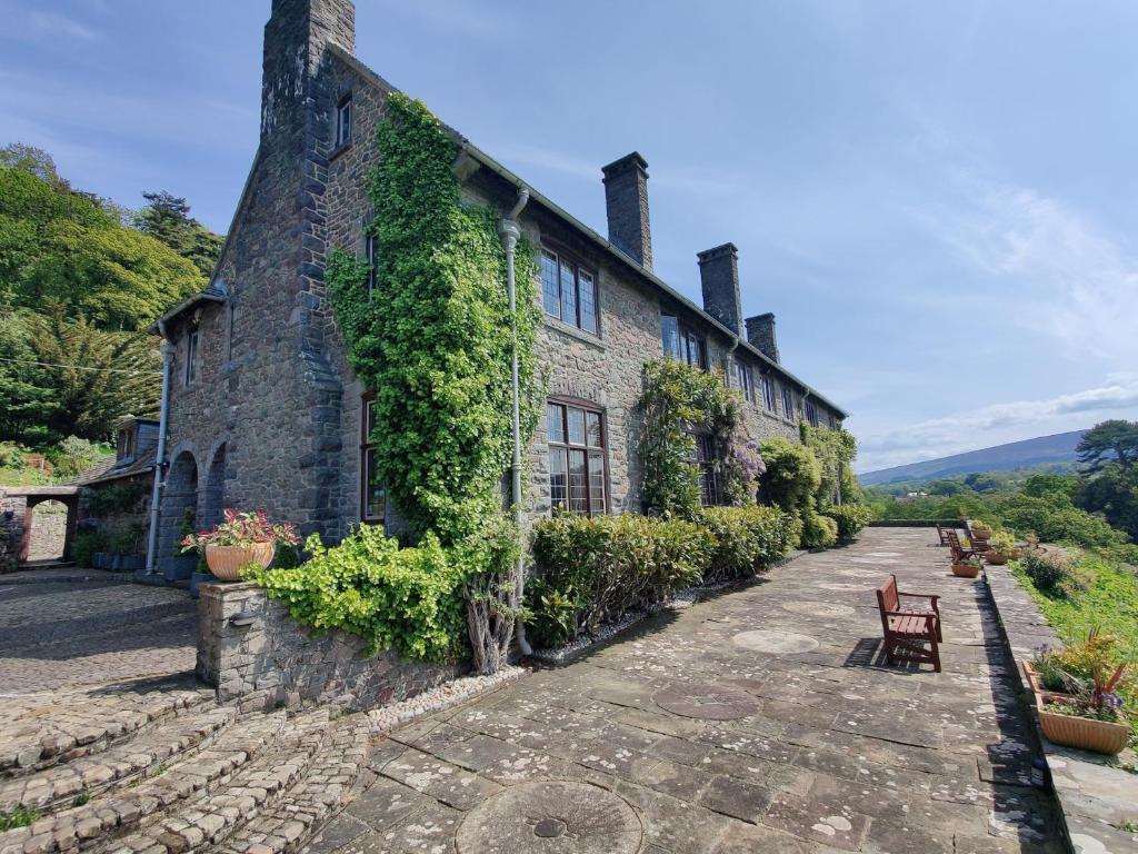 Una casa de piedra con hiedra a un lado. en Luxury Bed And Breakfast at Bossington Hall in Exmoor, Somerset, en Porlock