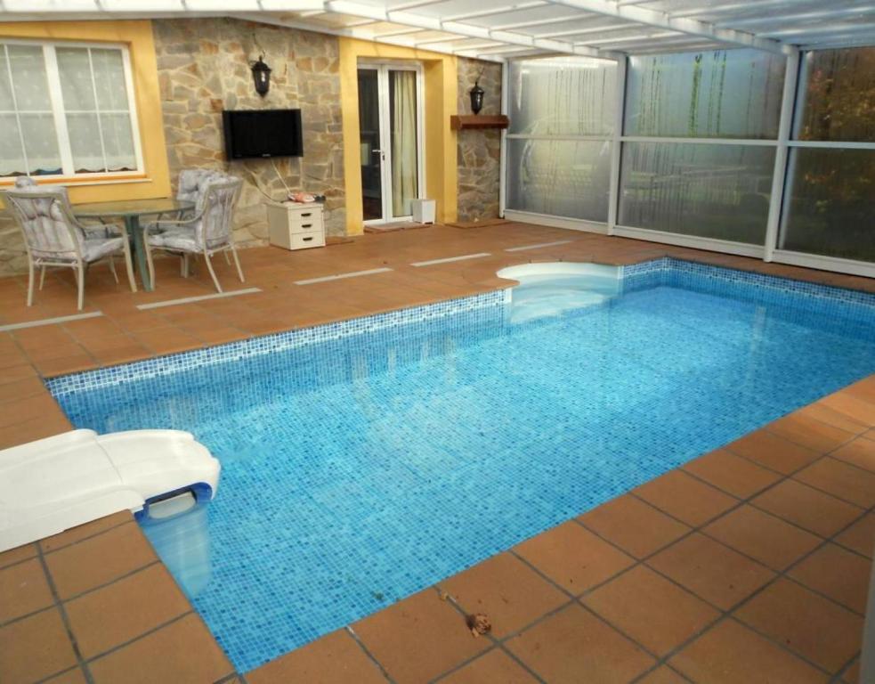 a large swimming pool with a table and a television at Piscina climatizada todo el año in Valle