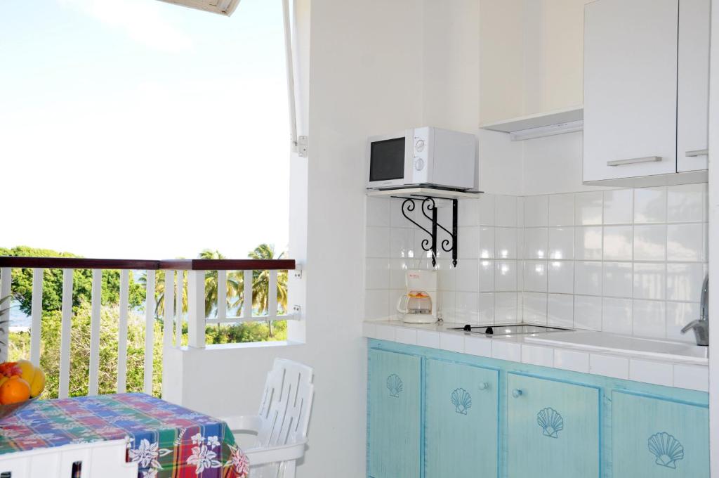 cocina con armarios azules, mesa y ventana en Résidence Tropicale, en Le Moule