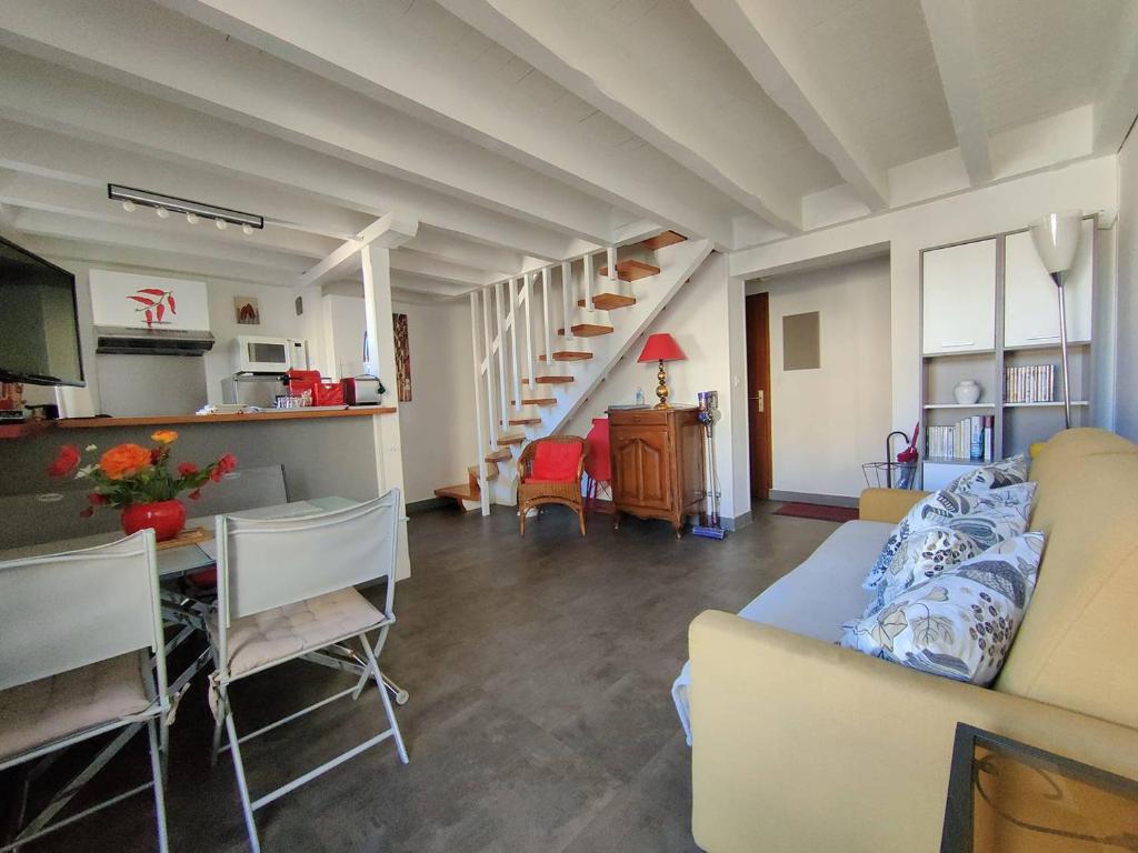 un soggiorno con un divano e un tavolo con sedie di St Jean de Luz, APPT Dupplex2 pers à 100 mètre de la plage a Sainte-Barbe
