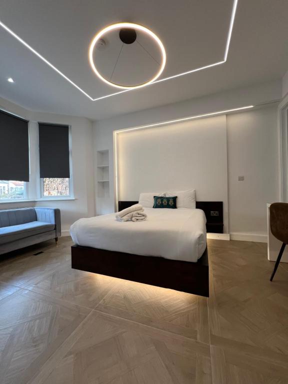 a bedroom with a large white bed and a ceiling at Luxurious London Studios in Harrow