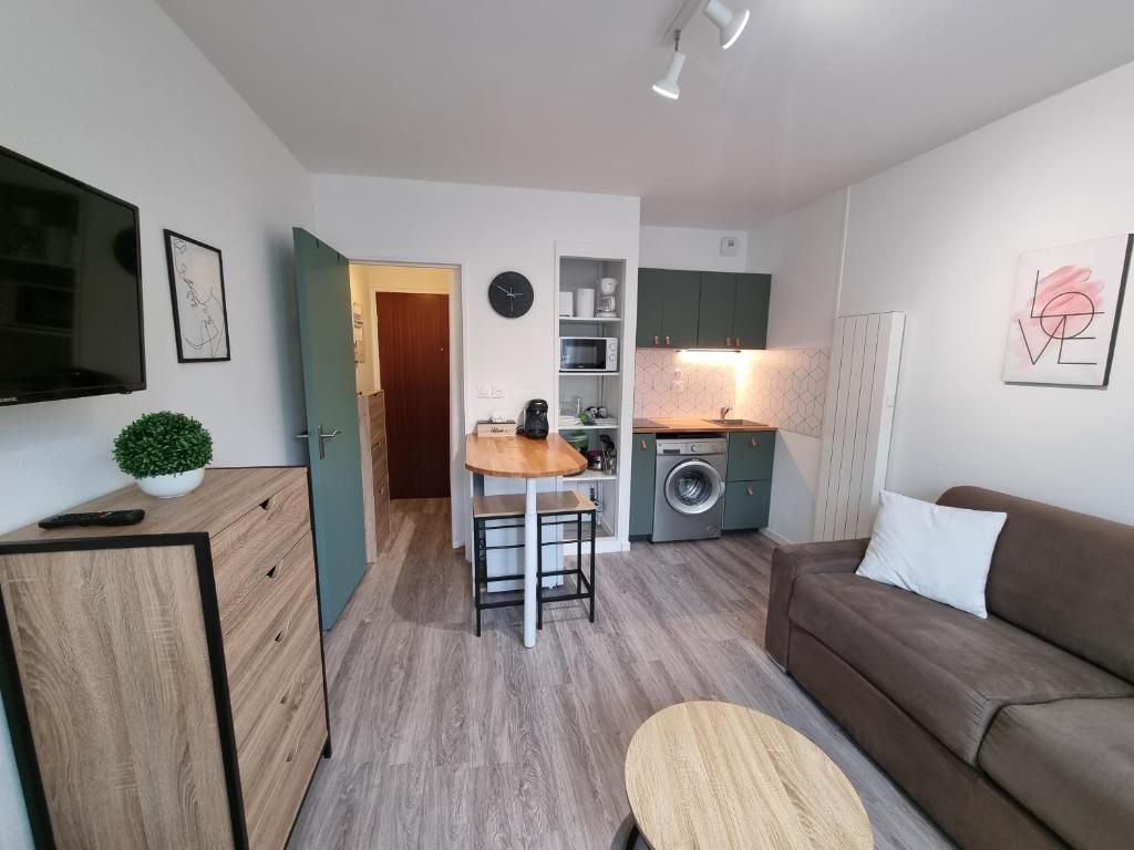 un salon avec un canapé et une cuisine dans l'établissement Echappée en bord de mer - studio à la plage !, à Courseulles-sur-Mer