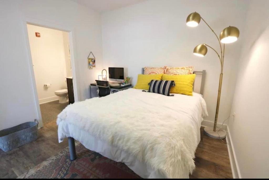 a bedroom with a white bed with yellow pillows at Hillsborough Street Flat in Raleigh