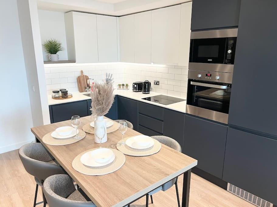2bedroom luxury apartment city centre V في مانشستر: مطبخ مع طاولة وكراسي خشبية في مطبخ
