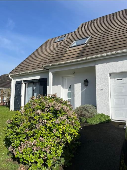 une maison blanche avec un grand bush devant elle dans l'établissement Belle maison familiale avec parking, à Épron