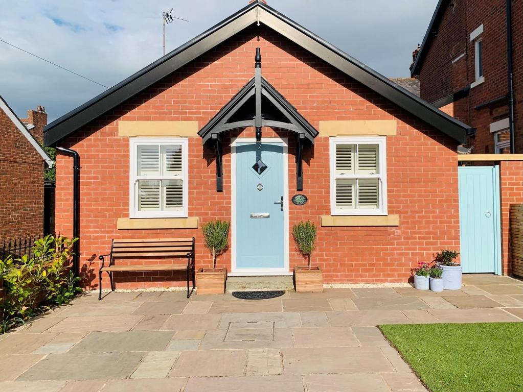 een rood bakstenen huis met een blauwe deur en een bank bij 1 Bed in Lytham 86044 in Saint Annes on the Sea