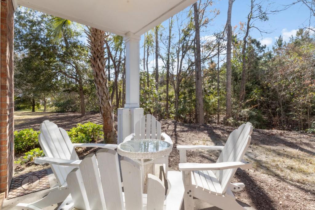 a porch with white chairs and a glass table at Arbor Trace #811 condo in North Myrtle Beach