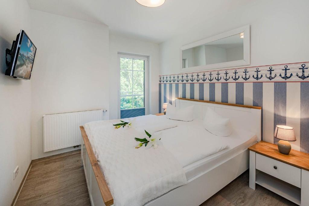ヘリングスドルフにあるVilla Doris Whg 4 Sonnenblickのベッドルーム(花の飾られた白い大型ベッド付)
