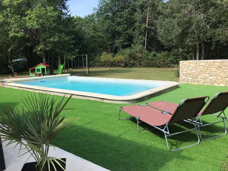 - une piscine avec 2 chaises et un palmier dans l'établissement Maison calme proche Périgueux et piscine chauffée, à Agonac