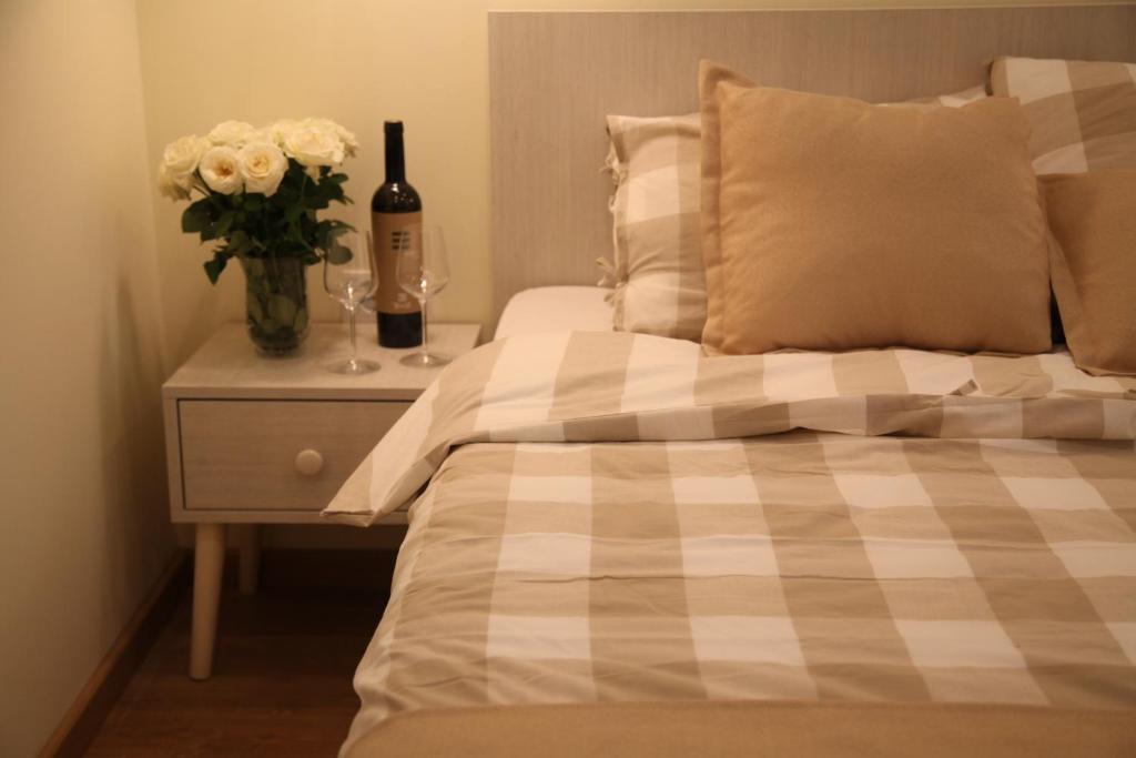 Una cama con un jarrón de flores y una botella de vino en Bed&Breakfast kod Smilje en Belgrado