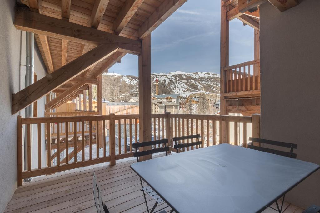 - un balcon en bois avec une table et des chaises sur une terrasse dans l'établissement La Maya - Appt vue montagne, à Vars