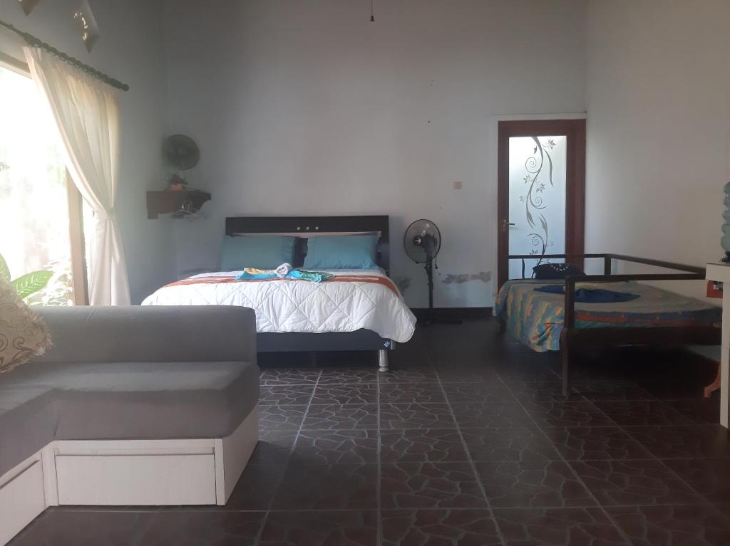 1 dormitorio con cama, sofá y ventana en Bali Homestay en Tejakula