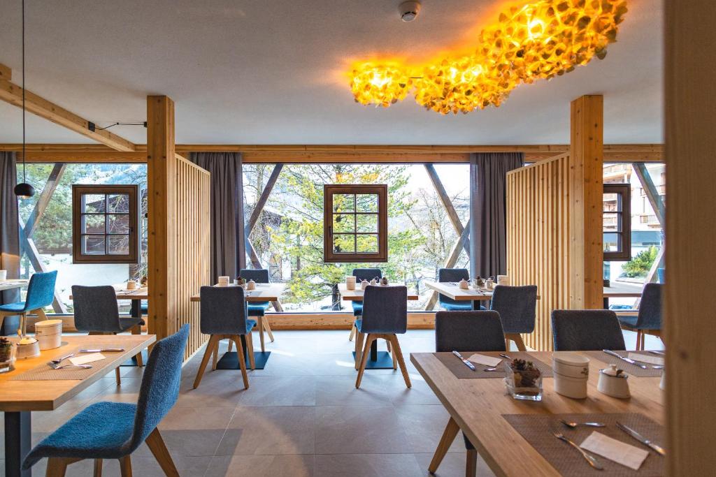 un restaurante con mesas y sillas de madera y ventanas en Garni Residence Alnö - Adults Only en San Vigilio Di Marebbe