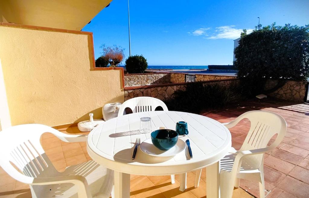 a white table and chairs with a view of the ocean at Apartamento en primera linea de mar en Pals 306-1 2H in Pals