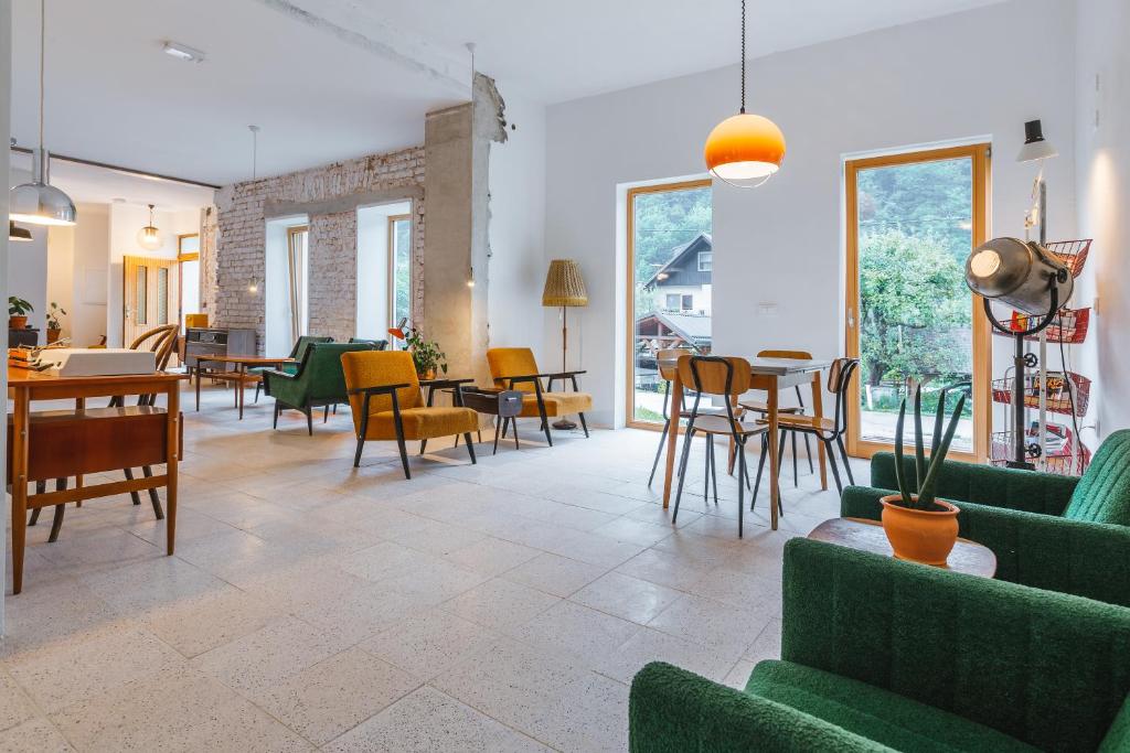 una sala de estar con muebles verdes, mesas y sillas en 2nd Station Hostel, en Bled