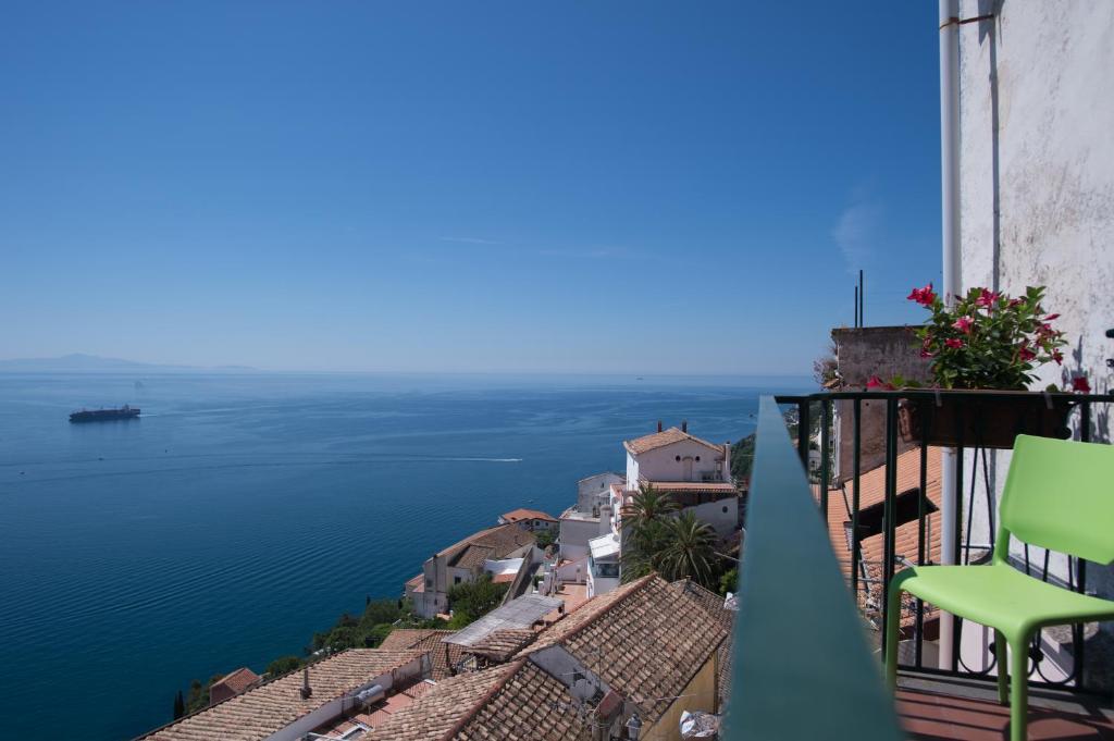 a green chair sitting on a balcony overlooking the water at Beatrice Apartment Sea View in Vietri