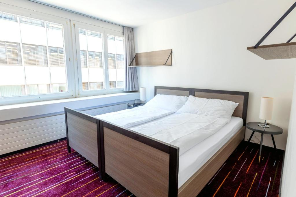 ein Schlafzimmer mit einem großen Bett in einem Zimmer mit Fenstern in der Unterkunft Union Light - Self Check-In Hotel in Luzern