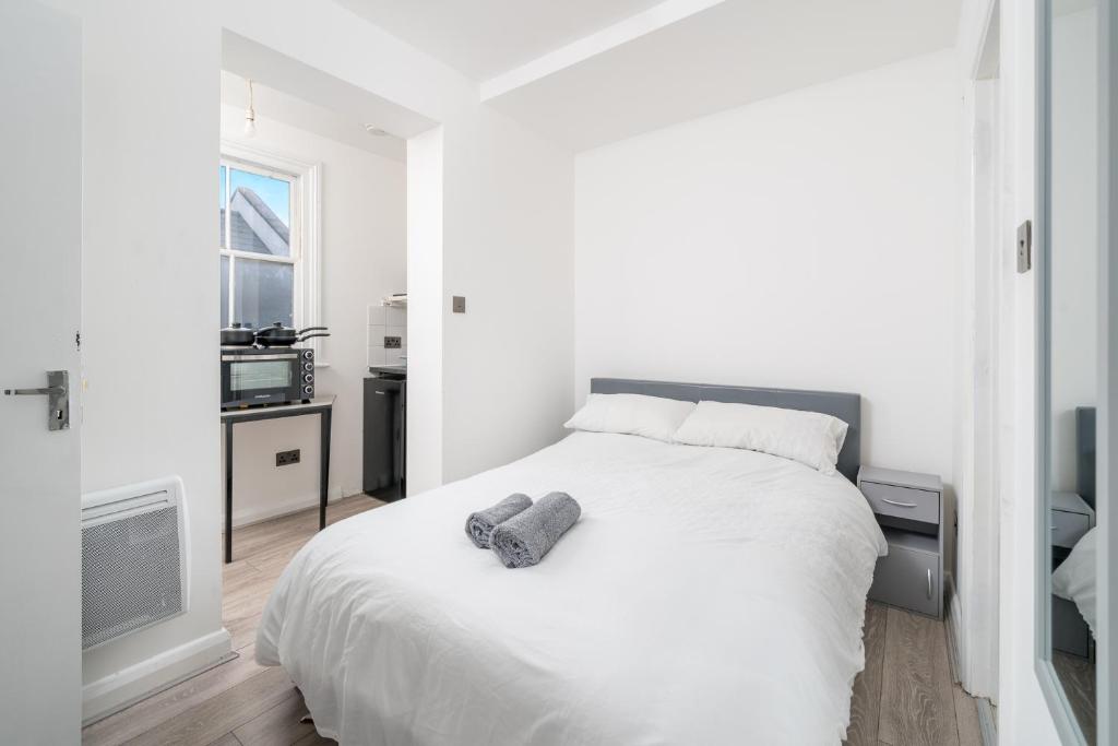 ein weißes Schlafzimmer mit einem weißen Bett und einem Fenster in der Unterkunft Heart of Dalston- Trendy Compact Studio Flat in London