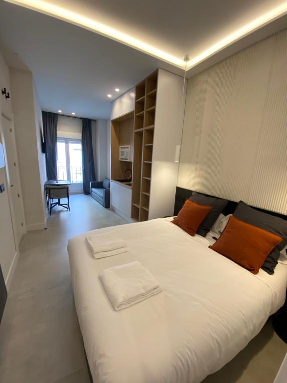 1 dormitorio con 1 cama blanca grande con almohadas de color naranja en Apartamentos "El collado Suites" Soria Centro, en Soria