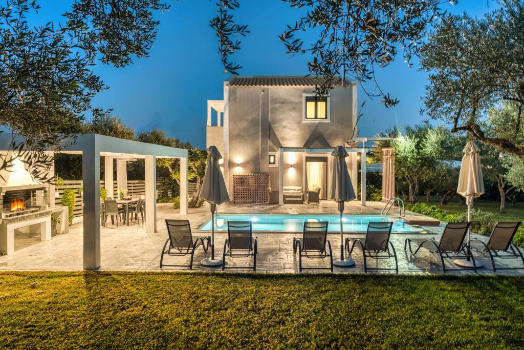 a backyard with a pool and chairs and a house at Valeria Private Villa in Planos