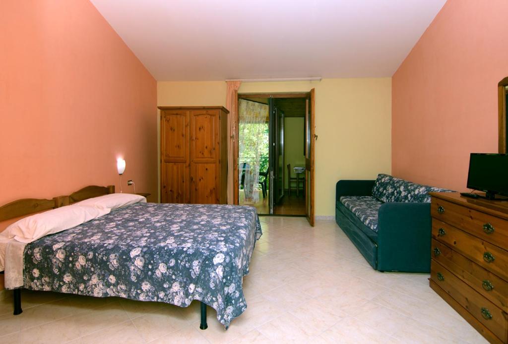 - une chambre avec un lit et un canapé dans l'établissement Le Acacie, à Castellammare di Velia