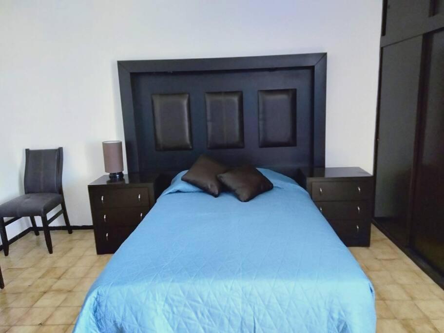 ein Schlafzimmer mit einem großen blauen Bett mit zwei Nachttischen in der Unterkunft Casa Sol, Residencia para Grupos 22 personas, Cerca a la FERIA in Aguascalientes