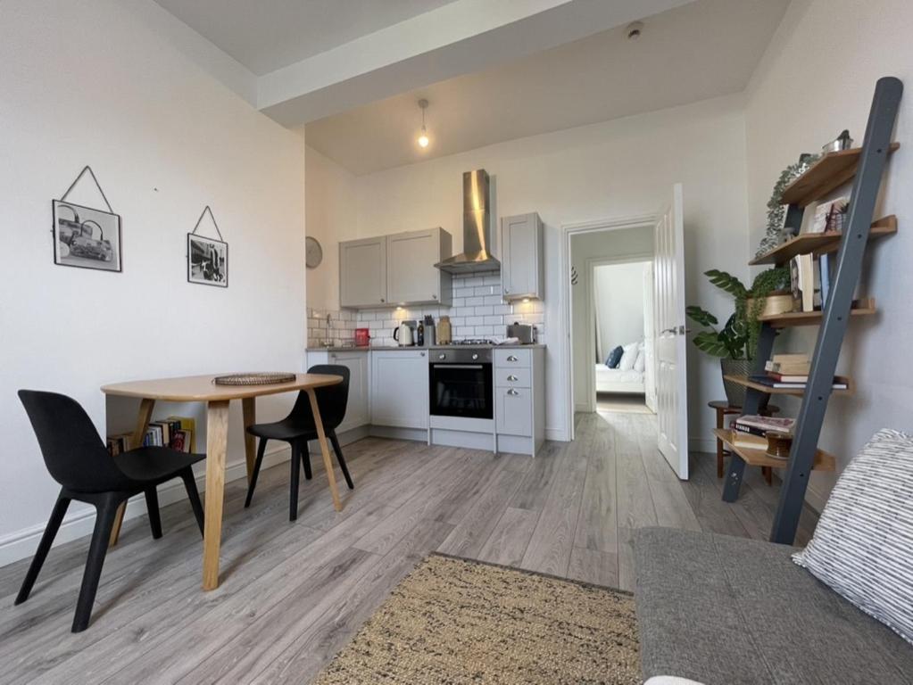 eine Küche und ein Wohnzimmer mit einem Tisch und Stühlen in der Unterkunft Apartment 2 St Georges in Cheltenham