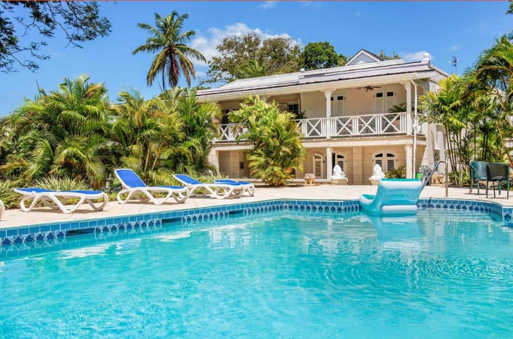 a villa with a swimming pool in front of a house at La Hacienda Bellevue in Bridgetown