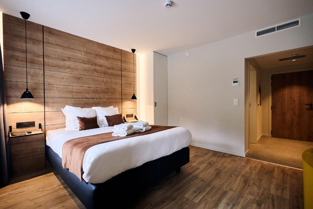 Schlafzimmer mit einem großen Bett mit einem Kopfteil aus Holz in der Unterkunft Le Mont Rigi in Weismes