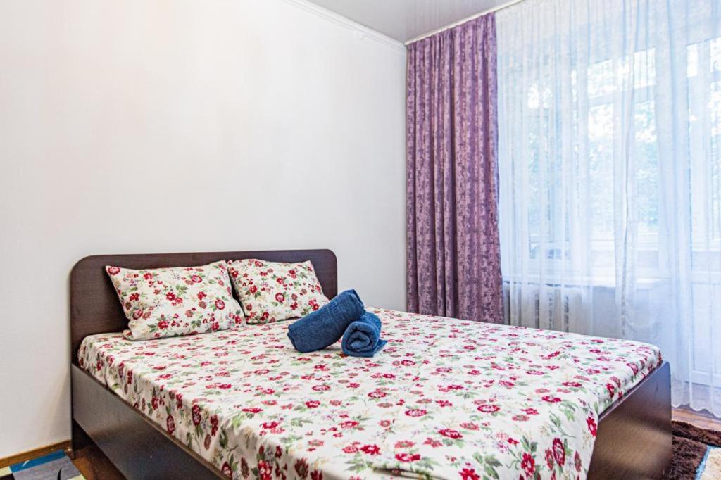a bedroom with a bed with a flowered blanket and a window at Maulenova 32.36 kv41 in Almaty