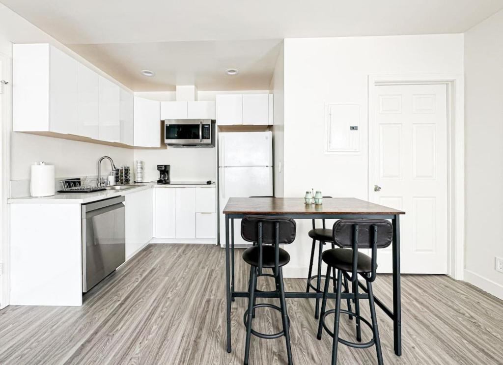 a kitchen with white cabinets and a table with stools at Cozy Guesthouse in LA (WO2 - BUR) in Burbank