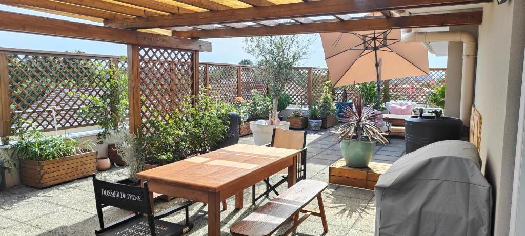 um pátio com uma mesa de madeira, cadeiras e plantas em appartement avec grande terrasse em Le Blanc-Mesnil