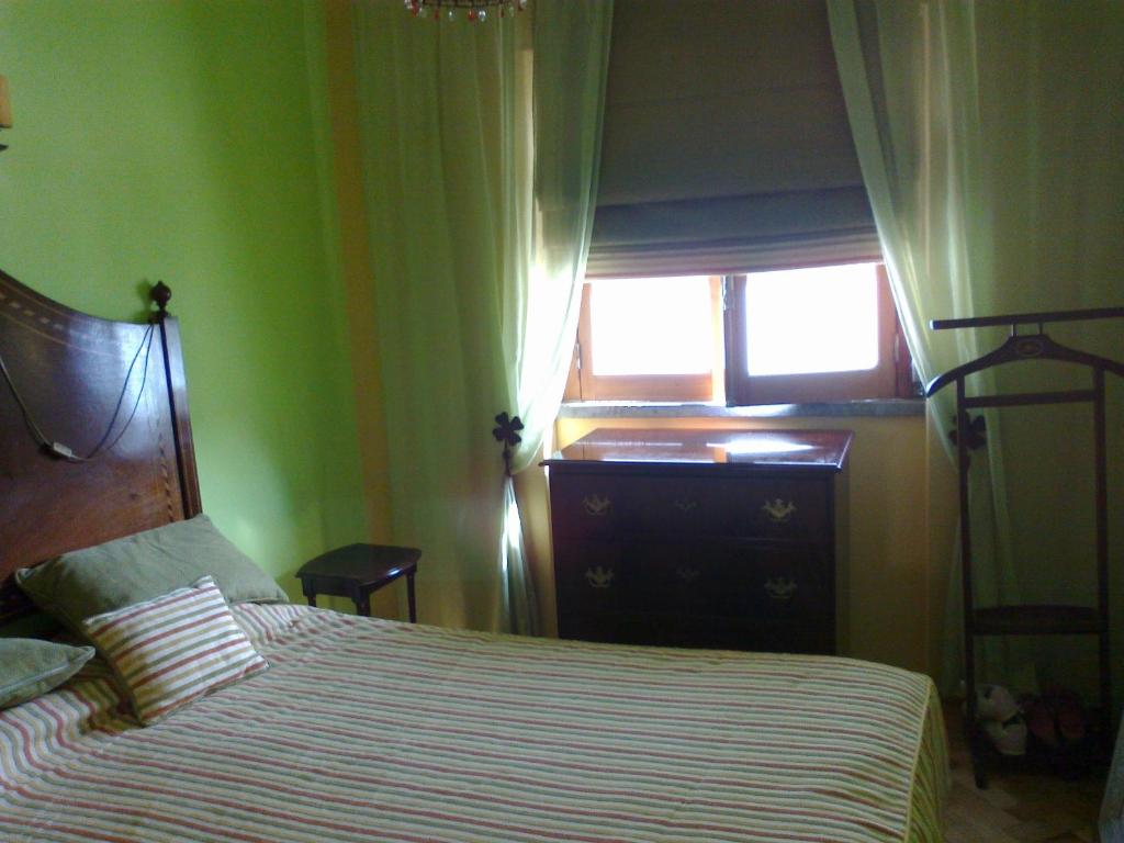 a bedroom with a bed with a dresser and a window at Casa Da Avó 2 in Ericeira