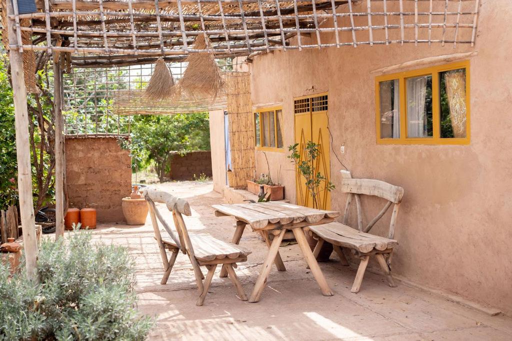 a wooden table and chairs sitting outside of a house at La Ferme des Tipis Marrakech in Marrakech