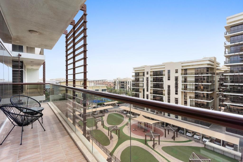 un balcón con sillas, mesas y edificios en Silkhaus Luxurious 1 BDR Next to Golf Course en Abu Dabi