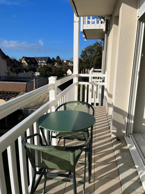 d'une table et de chaises vertes sur un balcon dans l'établissement CABOURG - 2 PIÈCES avec Balcon et parking- Hyper Centre et Plage, à Cabourg