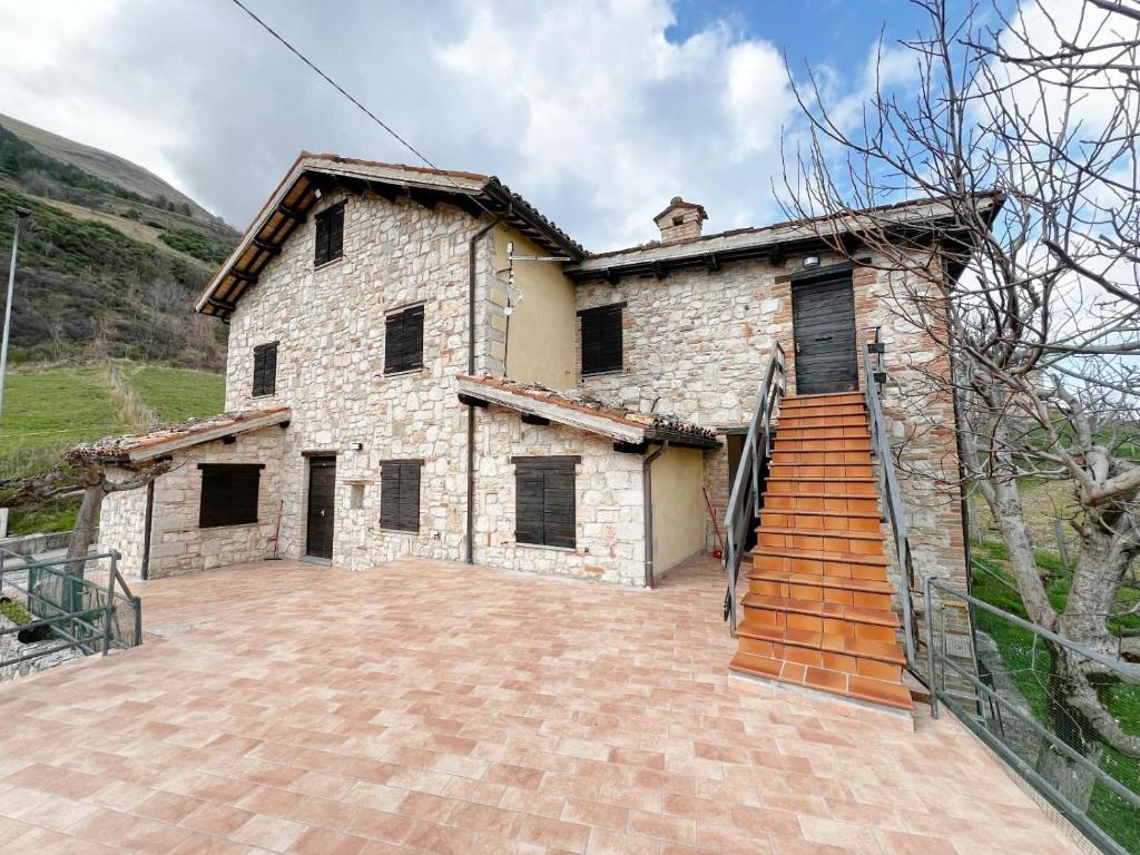 an exterior view of a stone house with a staircase at Il Tiglio in Montemonaco