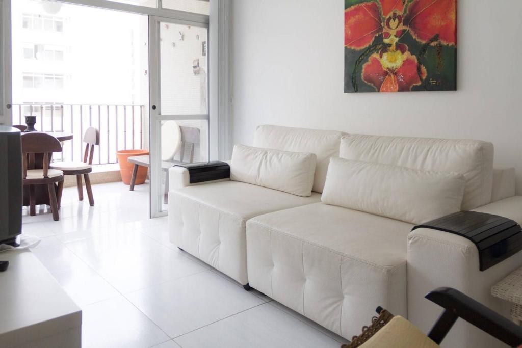 a white living room with a white couch and a table at Marisia in Guarujá