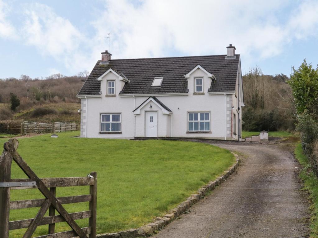 una casa blanca con una puerta y un camino de tierra en Gunn's Cottage, en Killyhevlin