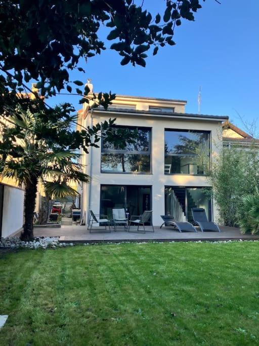 une grande maison avec des chaises et une cour dans l'établissement Maison Paris Stade de France Aeroports, au Blanc-Mesnil