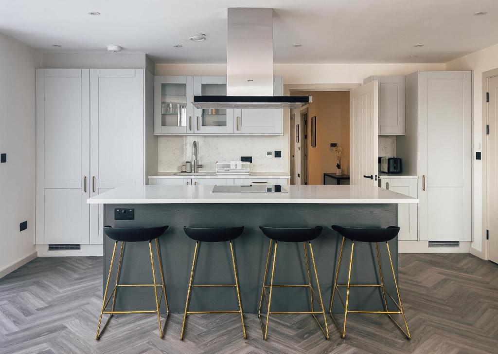a kitchen with a large island with three bar stools at Luxe Penthouse Retreat: With Free Parking! in Brentford
