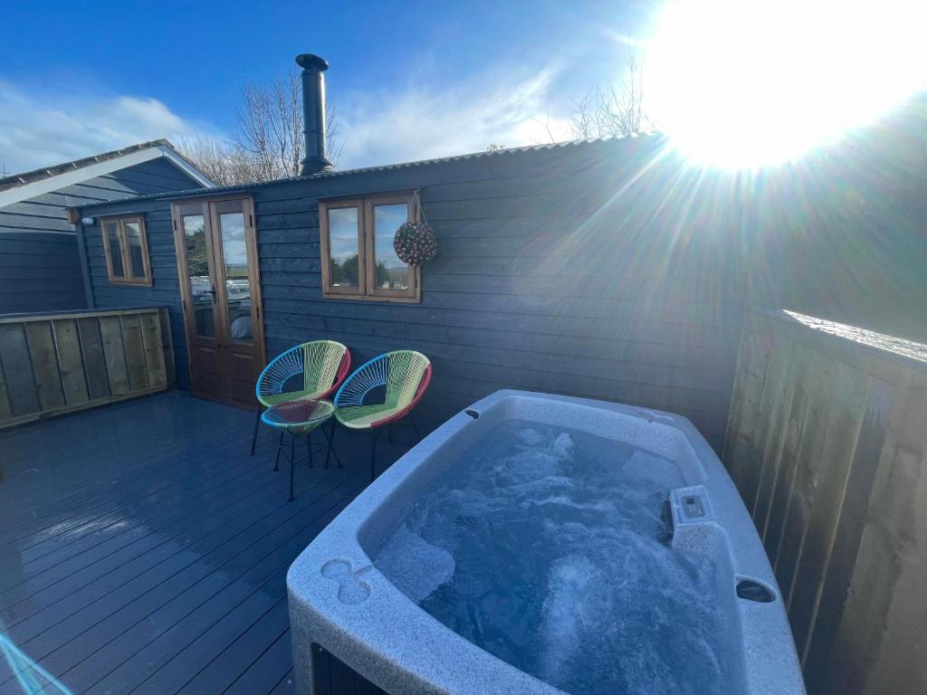 a hot tub on a deck with two chairs at Hafod Shepherd Hut in Aberystwyth
