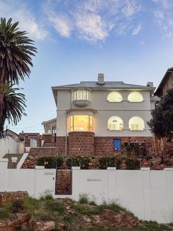 a house with a white fence in front of it at Kalimera Beach House in Mossel Bay