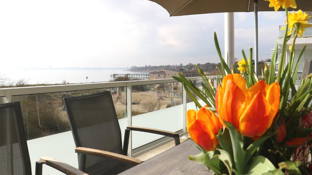 - une table avec un vase de fleurs sur le balcon dans l'établissement Südkap H-02, à Pelzerhaken