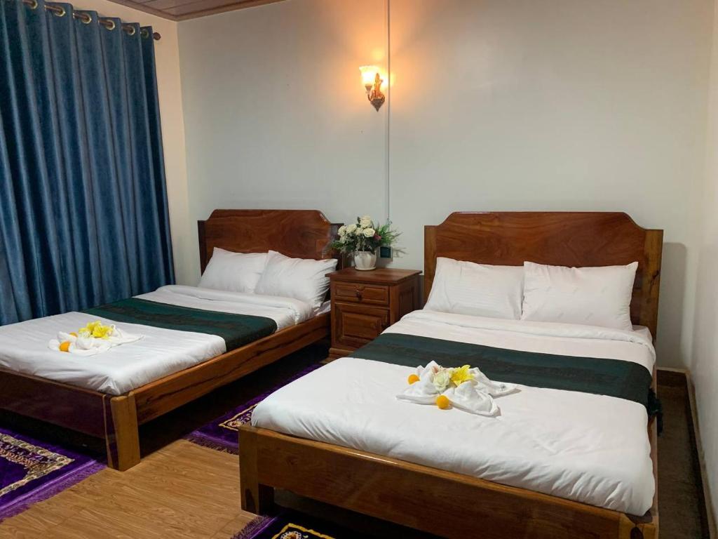 2 łóżka w pokoju hotelowym z jedzeniem w obiekcie Samnang Leap guesthouse w mieście Sen Monorom