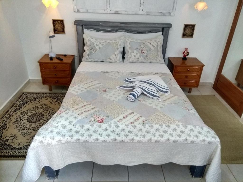 a bedroom with a bed with a white bedspread and two night stands at Pousada Casa Jardim in Serra Negra